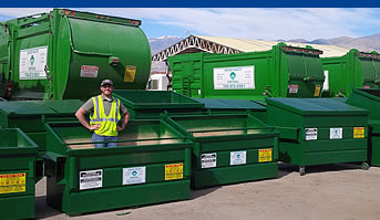 man standing in green dumpster